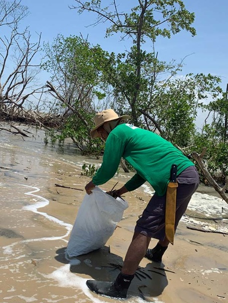 Mangroven-Pflanzer leert Sack mit Setzlingen an Strand
