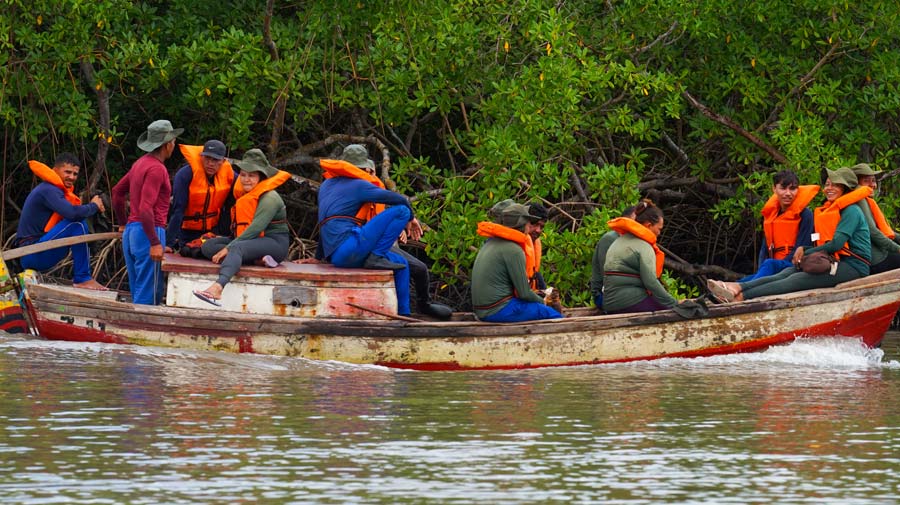 Baumpflanzerinnen in Booten mit Schwimmwesten
